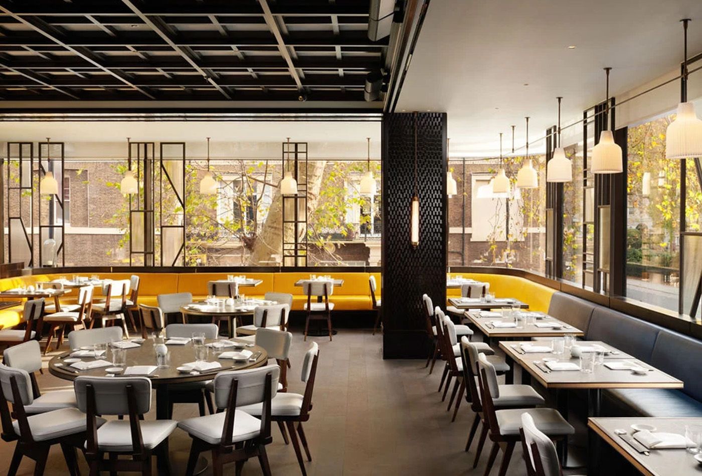 Dining area with pendant lights, grey chairs and a yellow dining bench spanning the room