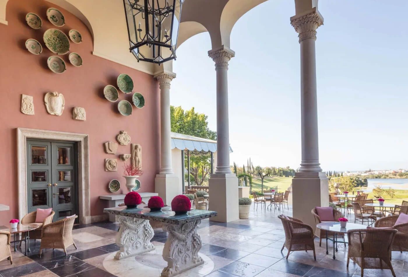 Marble floor terrace with pink pastel walls overlooking a picturesque view of the hotel grounds