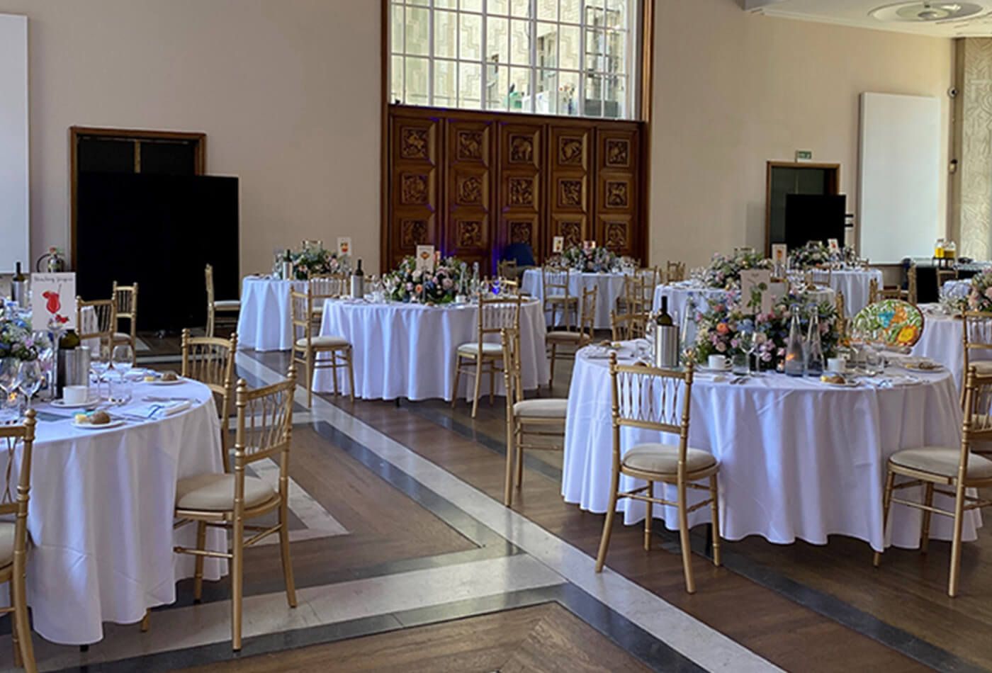 White wedding with gold chairs and round tables