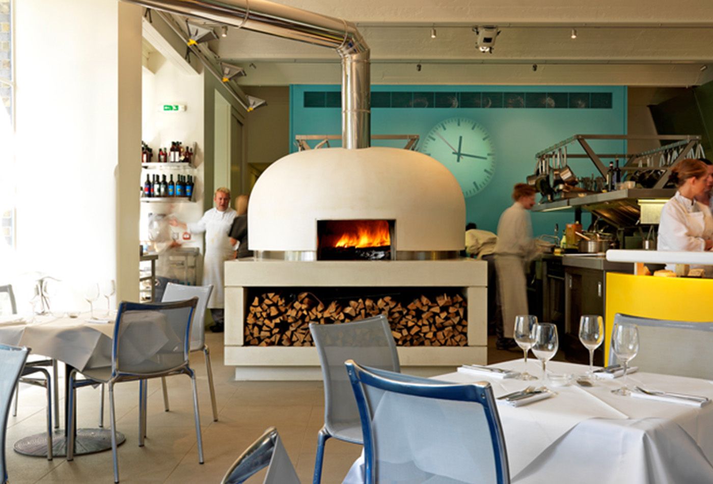 Large white pizza oven with a projected clock-face onto a turquoise wall