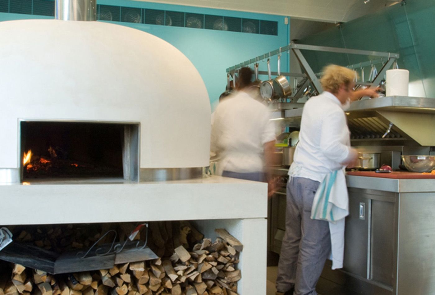 White pizza oven with chefs cooking in the background