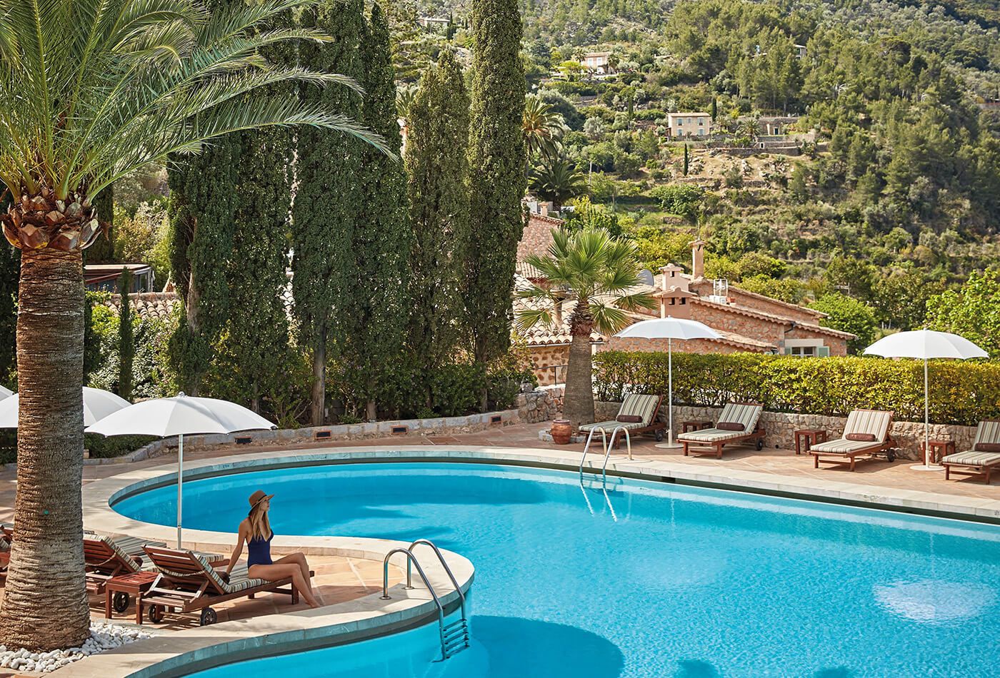 Bright blue swimming pool, palm trees and lady sunbathing