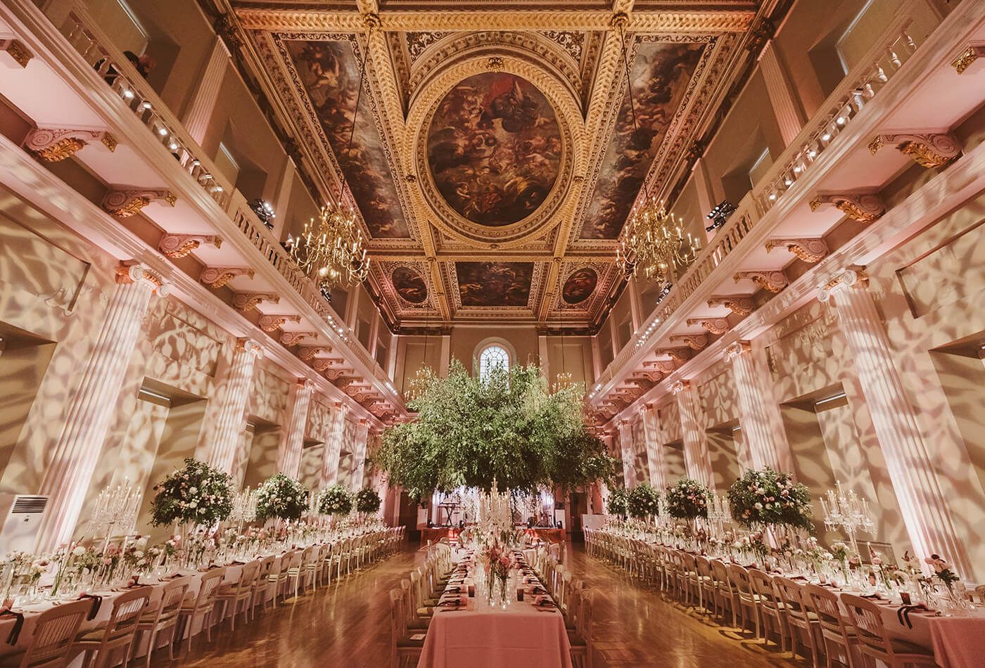 Pink floral wedding set up in large grand room with ceiling mural