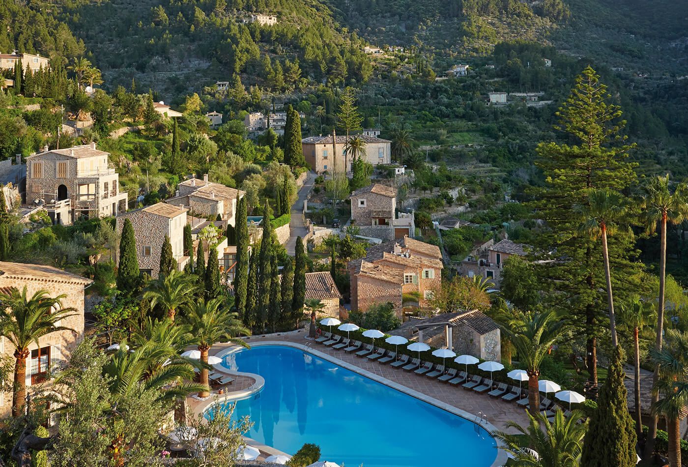 Drone shot of vast blue swimming pool surrounded by stone villas