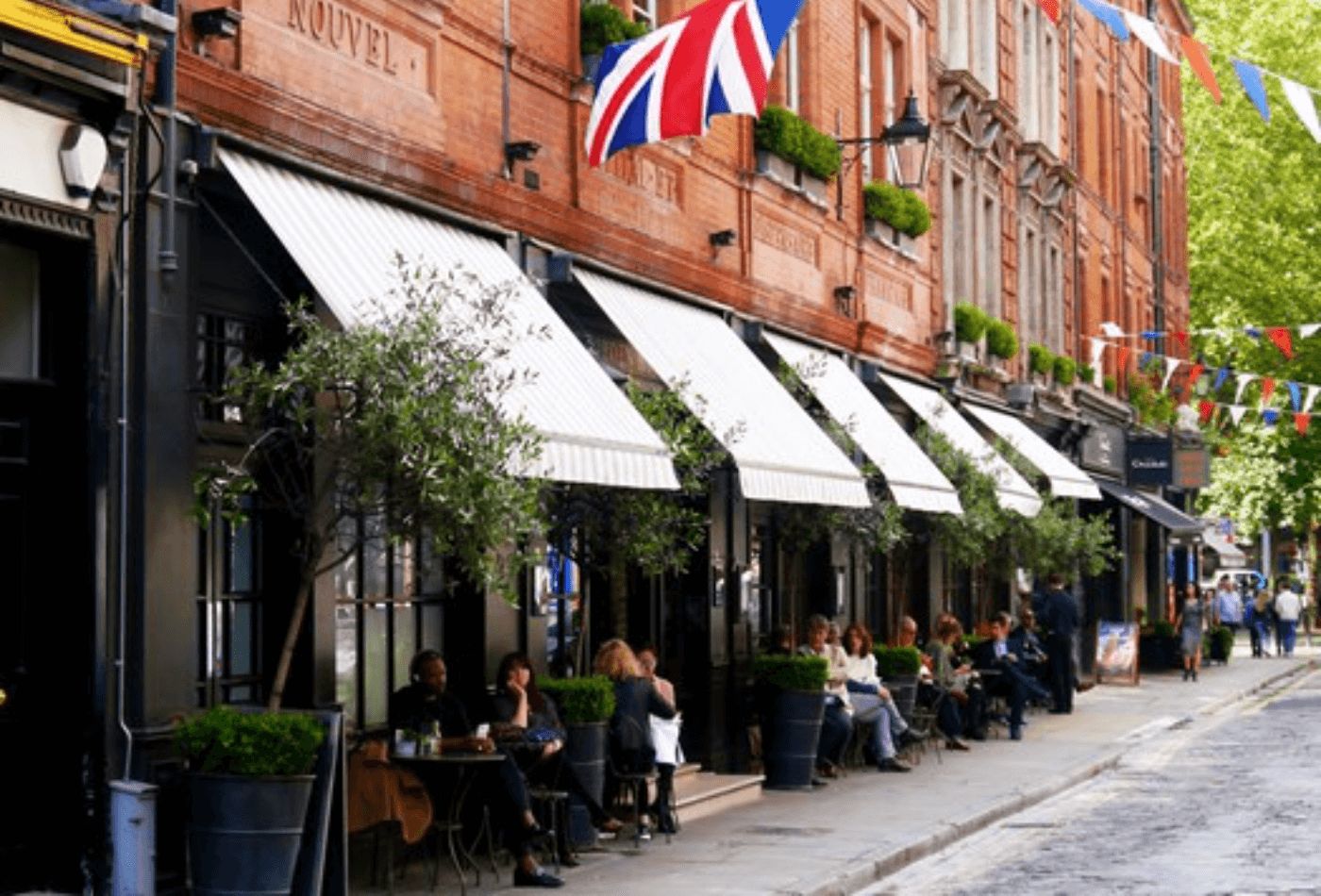 Red bricks, trees and striped awnings over outdoor seating area