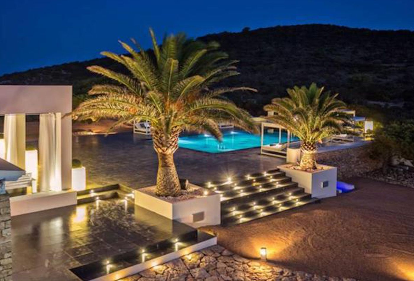 Evening shot of modern white building, swimming pool and palm trees