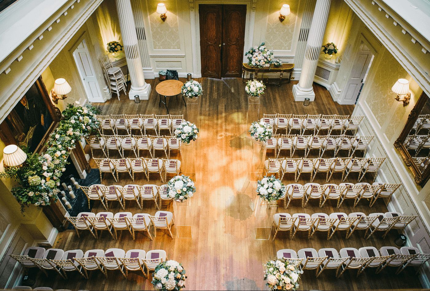 Wedding ceremony set up with greek pillars, pink floral arrangements and wooden floor