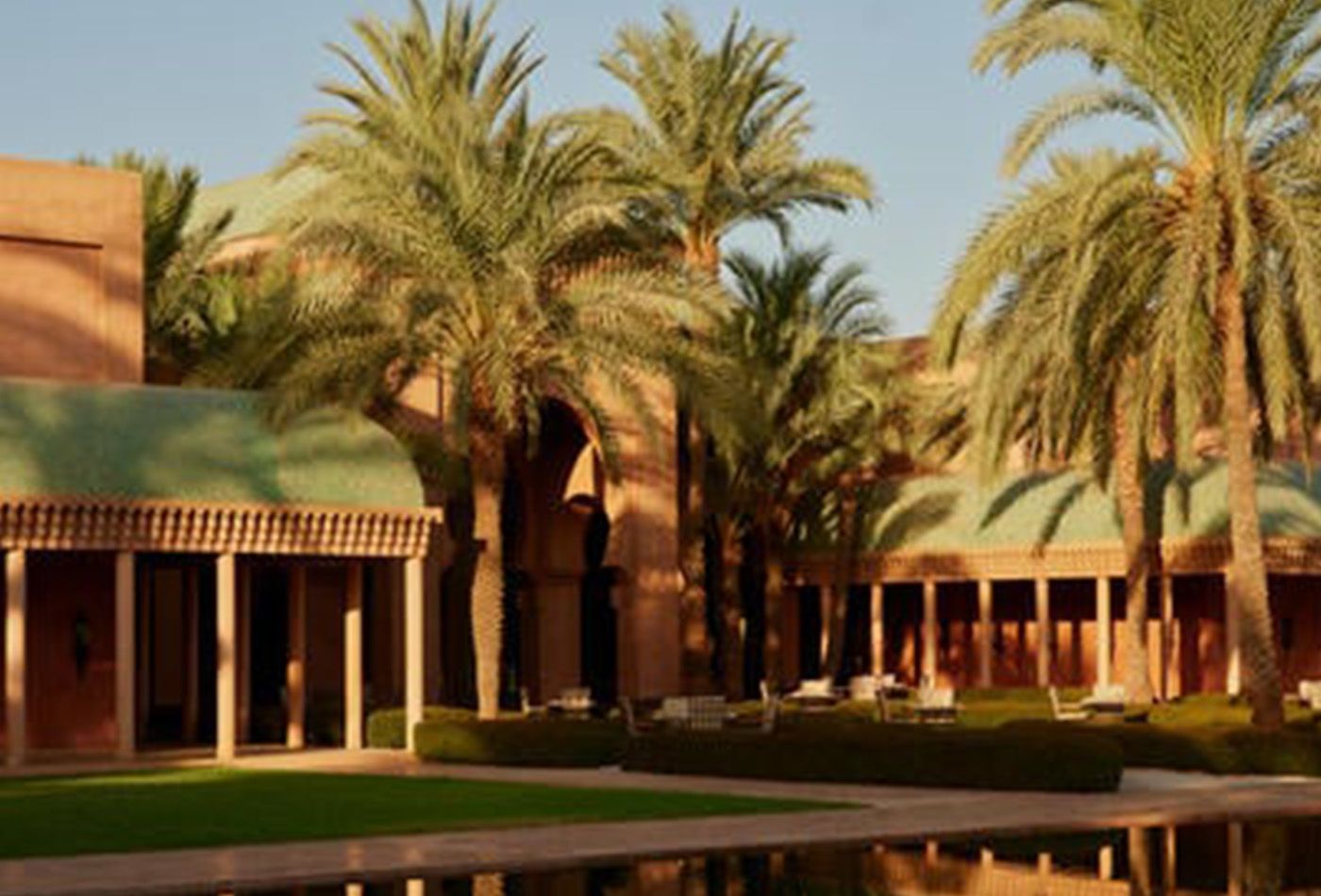 Shaded courtyard with terracotta coloured buildings with green vaulted roofs