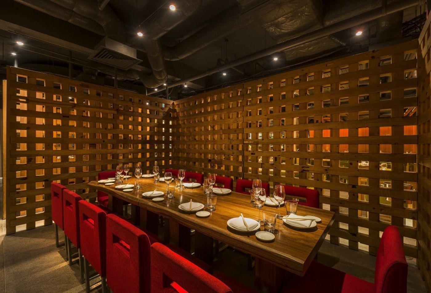 Long dining table with red seating and wooden Japanese room divider