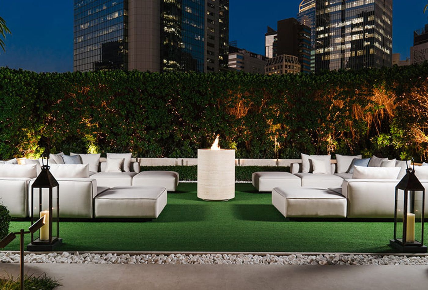 Rooftop bar with lawn, plants and sky scrapers in the distance