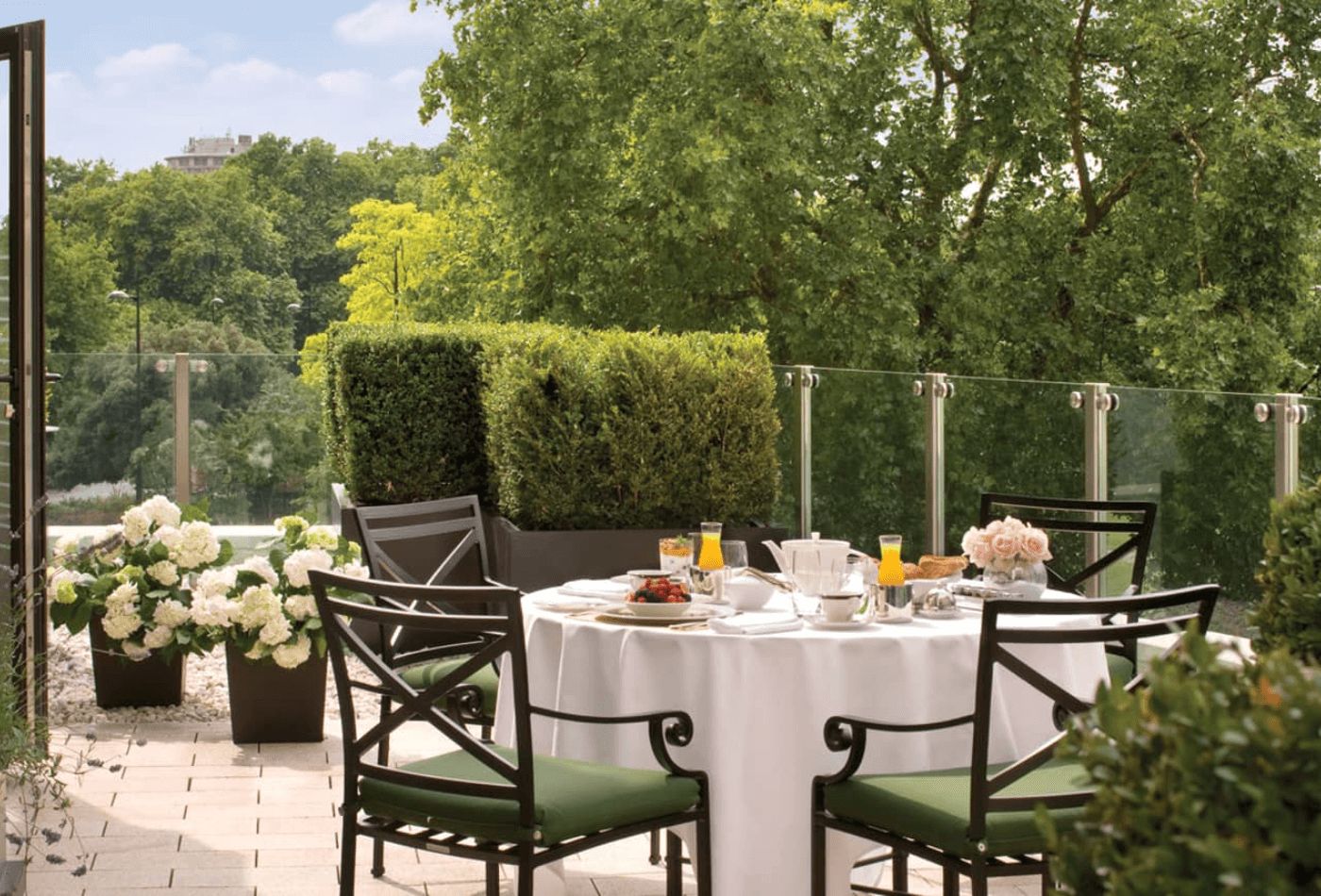 Four Seasons garden with black metal chairs, green cushions and white roses