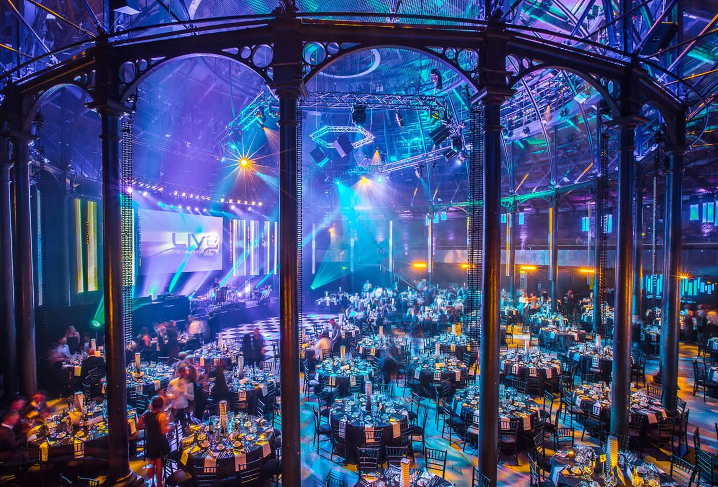 Vast iconic circular venue with many round tables set up for an awards ceremony