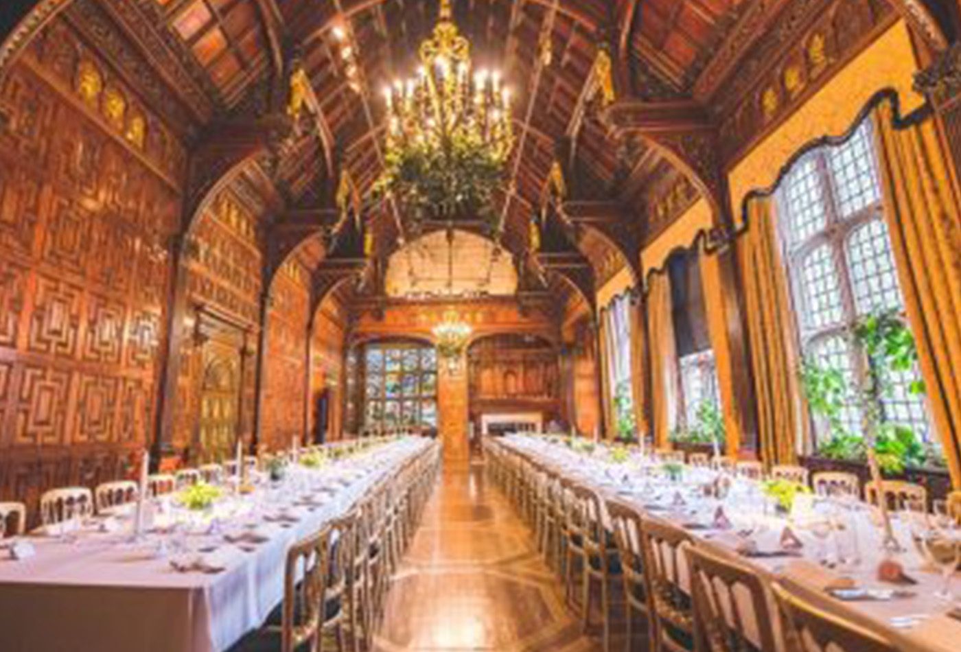 Long dining set up for wedding with beautiful stained glass windows, intricate wood carvings and plants