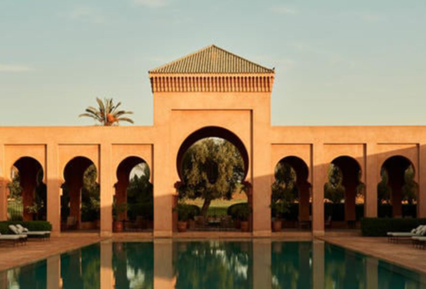 Large terracotta building overlooks a large swimming pool