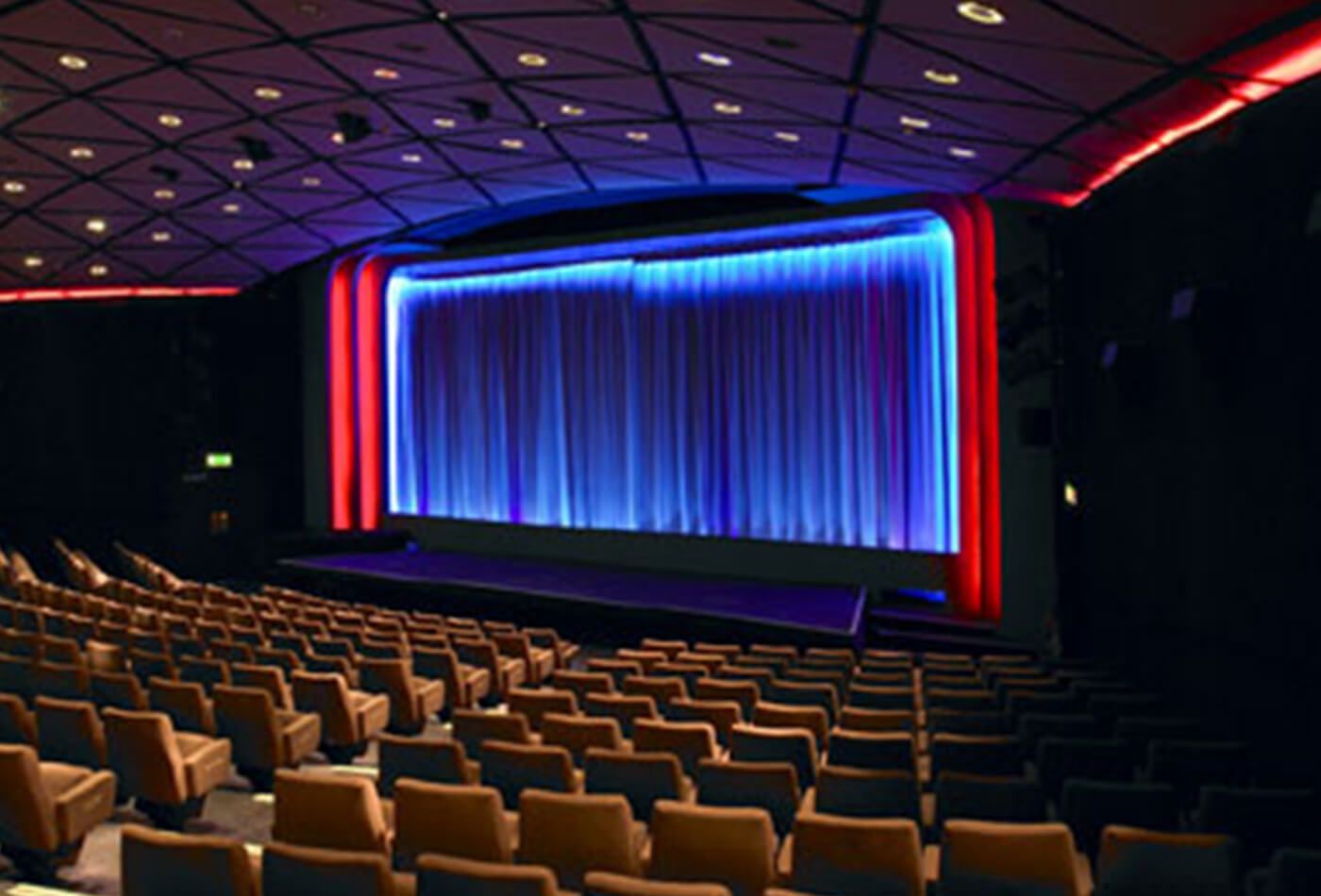 Interior shot of red velvet seats and stage lit up in blue